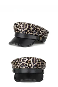 Detail view of leopard print beret with black PU leather brim and gold metal button