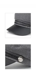 Detailed close-up of grey wool baker boy hat with black leather brim and silver metal button