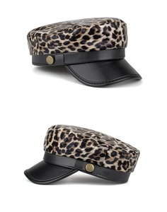 Detail view of leopard print beret with black faux leather brim and gold metal button