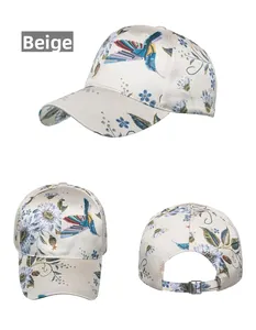 Detail view of beige satin baseball cap featuring hummingbird and floral embroidery