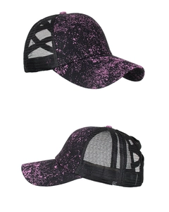 Detail view of black baseball cap with pink splatter pattern and X-shaped ponytail cross band