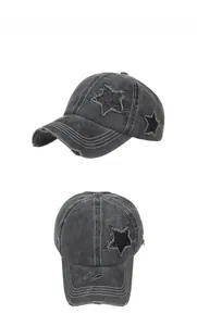 Detailed macro view of distressed charcoal denim cap with glitter star patch and white stitching