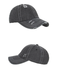 Detail view of washed black denim baseball cap with distressed holes and contrast stitching