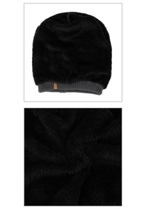 Detail of plush black faux fur beanie with grey ribbed knit cuff and leather tag