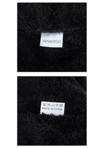 Detail of care label on black knitted hat showing 100% acrylic material and washing symbols