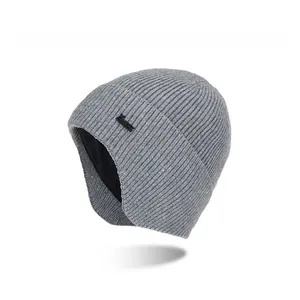 Detail of grey knitted ear flap beanie with thick warm texture and side patch