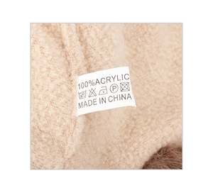 Detailed macro view of 100% acrylic knit hat with warm beige plush lining and care label