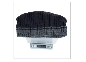 Detailed view of striped knit beanie on electronic scale weighing 63.0g for winter