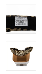 Detailed view of leopard print sun visor weight measurement and 100% polyester material label