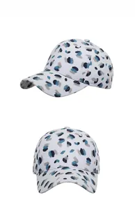 Detail view of white baseball cap with blue splatter graffiti and structured curved brim
