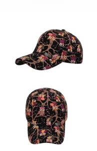 Detail view of cotton baseball cap featuring colorful cartoon owl prints on black fabric
