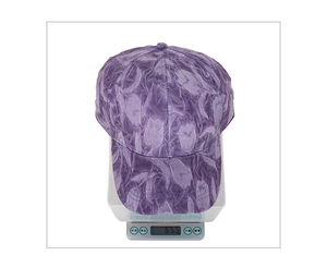 Macro shot of a purple floral baseball cap being weighed on a scale to show its 65.5g weight