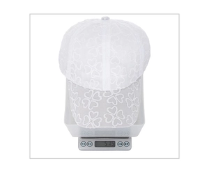Detailed top view of a white lace baseball cap weighing 51.5g on a digital scale