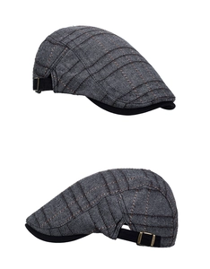 Détail d'une casquette gavroche à carreaux gris avec boucle en métal bronzé
