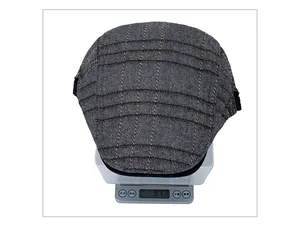 Vue de dessus d'une casquette gavroche grise à carreaux sur une balance pesant 84,4g