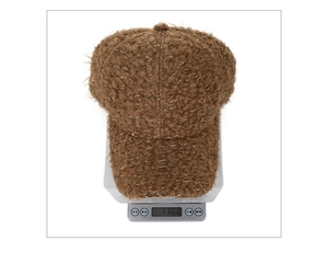 Vue détaillée d'une casquette en laine d'agneau marron pesant 110g sur une balance