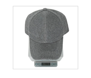 Detailed view of dark gray faux mink baseball cap on a scale showing its 102.1g weight