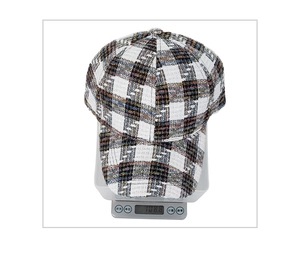 Detail shot of black and white plaid tweed baseball cap weighing 108.8g on a digital scale