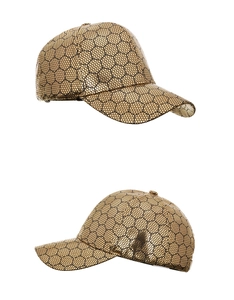 Detail view of gold baseball cap featuring black hexagonal honeycomb texture and curved brim