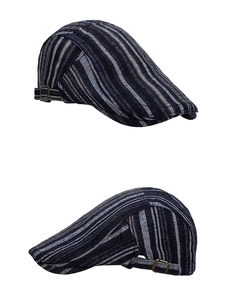 Detail view of the bronze metal adjustable buckle on a striped vintage flat cap hat
