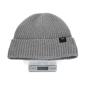 Grey ribbed knit beanie with leather patch on a digital scale weighing 112.8g