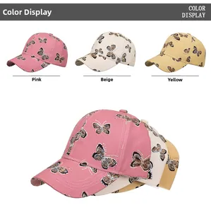 Dettaglio dei cappellini da baseball con motivo a farfalla in rosa, beige e giallo