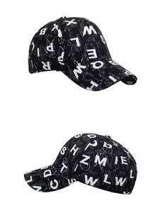 Close-up of black baseball cap with white letter prints and fine line art details