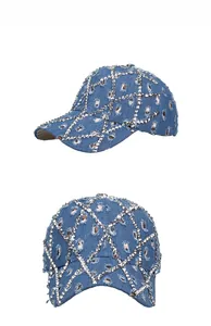 Detailed view of blue denim baseball cap with silver metal studs and distressed ripped holes