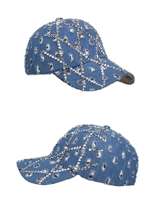Detailed close-up of washed blue denim baseball cap featuring distressed holes and silver studs