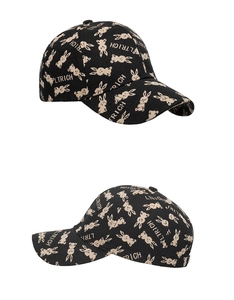 Detail view of black canvas baseball cap with beige rabbit pattern and letter embroidery