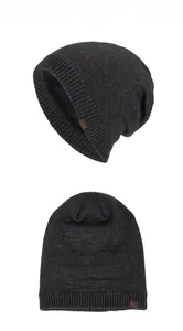 Detailed view of the dark gray knitted beanie with inner fleece lining and leather brand logo