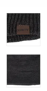 Macro detail of dark grey chunky knit beanie featuring a brown leather branded logo patch