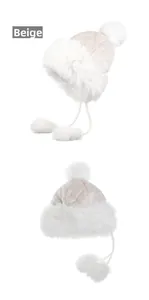 Detail view of beige quilted winter trapper hat with white faux fur lining and pom-poms