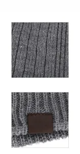 Detail of grey ribbed knit winter hat featuring a brown embossed leather XHBOY patch