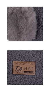 Detail of gray faux fur and fleece fabric with a sewn brown leather label on the pilot cap