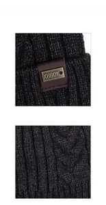 Detailed macro view of dark grey thick cable knit pattern and leather metal logo tag