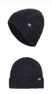 Close-up of dark grey cable knit texture and brown leather label on the warm beanie