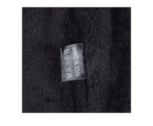 Detail des weichen schwarzen Fleecefutters und des Webetiketts einer Winterstrickmütze