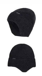 Detail of black rib-knit winter hat with thick fleece lining and silver metal logo plate