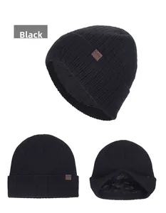 Dettaglio del berretto in maglia nera con spessa fodera in pile e logo in pelle marrone