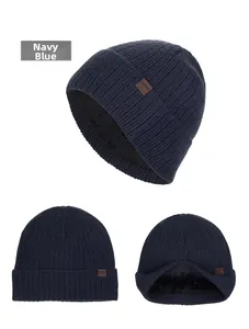 Dettaglio del berretto in maglia blu scuro con fodera in pile nero e toppa in pelle marrone