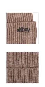 Close-up of brown ribbed knit beanie featuring a black embossed rubber brand logo patch