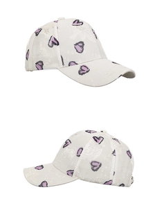 Dettaglio cappello beige in pizzo testurizzato con piccoli motivi a cuore viola