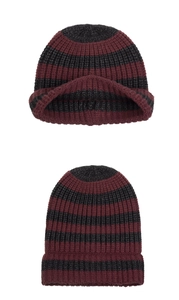 Detail of red and black striped knit beanie featuring thick texture and ribbed cuff