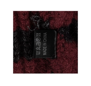 Detail of knit fabric with washing label and made in China tag on striped beanie