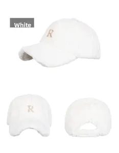 Close-up of white plush baseball cap with gold embroidered R letter and adjustable buckle