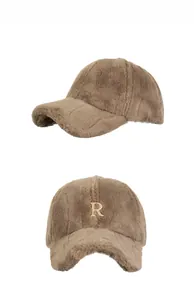 Detailed close-up of brown plush baseball cap with gold metal R badge on a white background