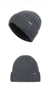 Detail of dark grey knit beanie with thick fleece lining and metallic logo badge
