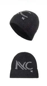 Detail of black knitted beanie showing grey NC letter pattern and woven brand logo tag