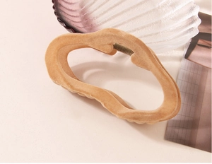 Dettaglio della molletta per capelli in velluto kaki con texture morbida e molla